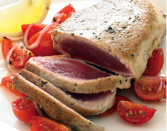 Seared tuna steak served with fresh tomatoes – premium quality seafood.