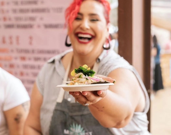 Woman presenting a seafood dish with a big smile.